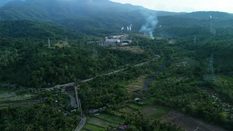Bird's-eye captures mountains, vibrant green forests and smokestack emitting. Stock Footage 336808218