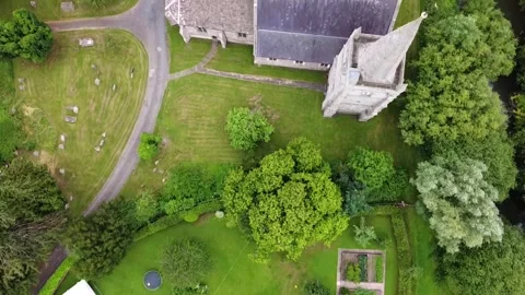Bird's-Eye Drone View Over a Village Church, Spire, Graveyard, and Lush Grounds Stock Footage 281851776