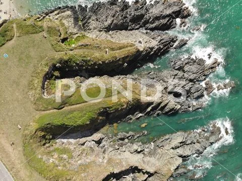 Birds eye shot of blue water crashing against interesting coastal rock Stock Photos