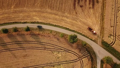 Birds eye tracking shot of tractor leaving field and encountering traffic Stock Footage 117988576