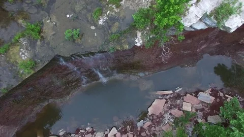 Birds eye turn down over waterfall &amp; small pool of water beneath Stock Footage 80270826