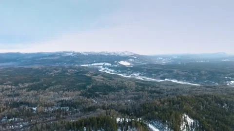 Bird's-eye view of a dense forest, frozen Tetsa River and snow-capped mountains Video stock 139118138