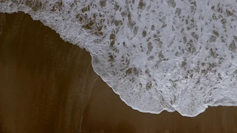 Bird's-eye view of an empty sandy beach. The waves are rolling on the shore Stock Footage 231704582