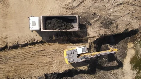 Birds eye view of excavator digging dirt and loading it into a truck Stock Footage 293012197