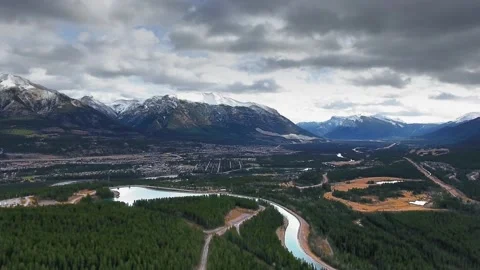 Bird's-eye view of a forest river and the city surrounded by mountains (Alberta) Stock Footage 137513255