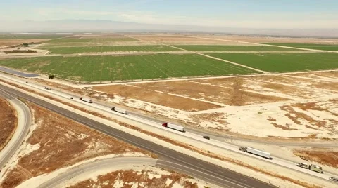 Bird's eye view of freeway traffic by agricultural farmlands Stock Footage 53775324