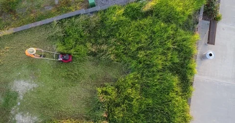 Birds eye view of man working hard mowing long grass 스톡 동영상 75956729