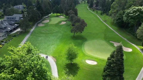 Birds-eye view of manicured golf green surrounded by sand bunkers trucking right Stock Footage 337713476