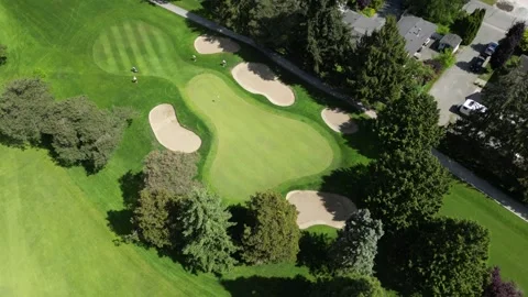 Birds-eye view of manicured golf green surrounded by sand bunkers orbiting Stock Footage 337713530