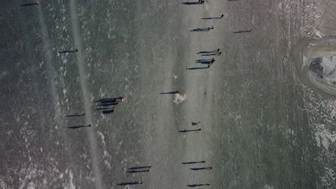 Birds eye view of many people walking and ice skating on frozen fjord Stock Footage