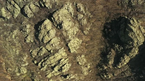 Birds eye view of mountain hillside rocks below drone flight Stock Footage 182299982