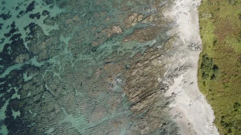 Birds eye view of the ocean, rocks, sand and green coast of New Zealand Stock Footage 86530504