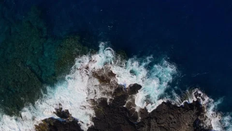 Bird's eye view of ocean waves crashing against a rocky beach in Hawaii Stock Footage 132770471