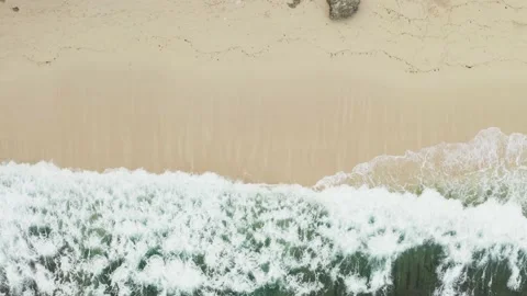 Bird's eye view of ocean waves crashing against an empty sand beach. Stock Footage 135679208