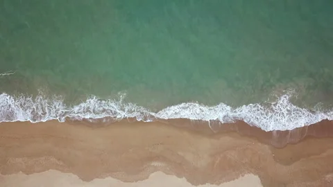 Bird's eye view of ocean waves crashing against an empty beach Stock Footage 153279718