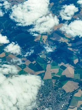 Bird's eye view of patchwork fields and clouds over a quaint town in the ea.. Stock Photos