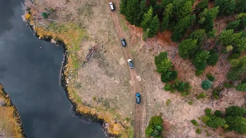 Birds Eye View Range Rover SUVs Driving Beside a Lake and a Forest Stock Footage 165646107