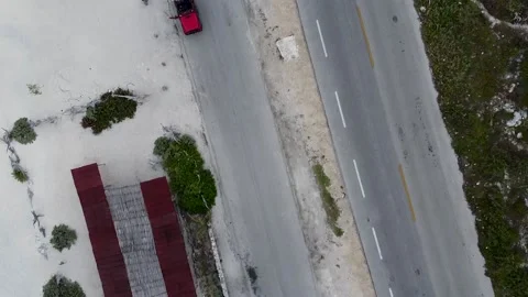Birds-eye view of a red jeep car parking on a coastal small road next to a Stock Footage 135596512
