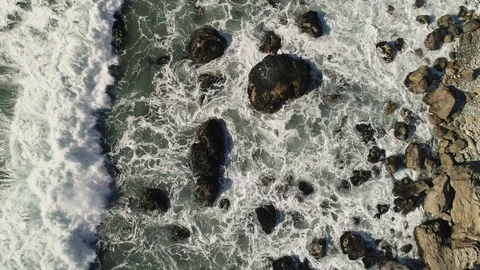 Birds eye view slowly rotating up over a rocky shore with waves crashing. 库存影片 87951150