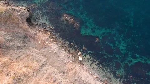 A bird's-eye view of the steep coast at the transparent turquoise sea with a  Stock Footage 131801870