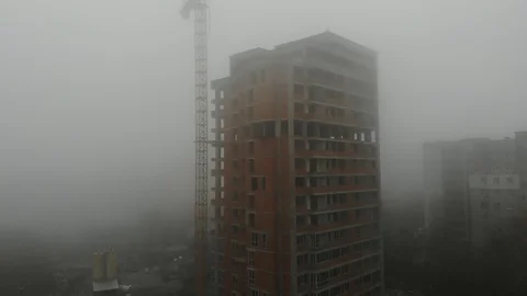 Birds eye view on tower crane in fog standing next to residential building Stock Footage 123610959