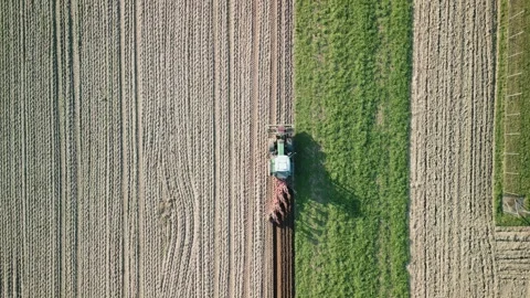 Birds eye view: tractor and trailer plowing brown soil field, spring farming Stock Footage 341122267