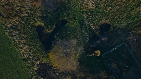 Bird's-eye View of a Tractor Digging a Pond in a Field - Aerial Pull-up Shot Video stock 331174854