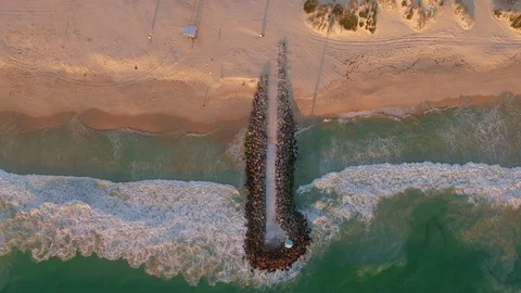 Birds eye view waves on a beach with a rock break Stock Footage 94146009