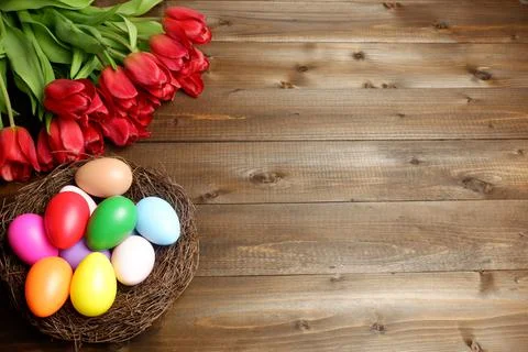 Birds nest with multicolored easter eggs and bouquet of red tulip flowers 스톡 사진