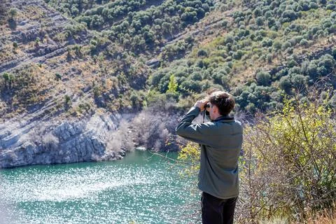 Birdwatcher looking at the sun reflection on the water Photos