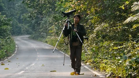 Birdwatcher with scope and binoculars on abandoned road. Stock Footage 121617665