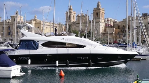 Birgu, Malta - big yacht goes along harbor and picturesque city buildings view Stock Footage 70890341