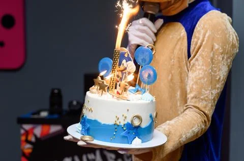 Birthday cake with decorative elements held by performer in costume Foto stock