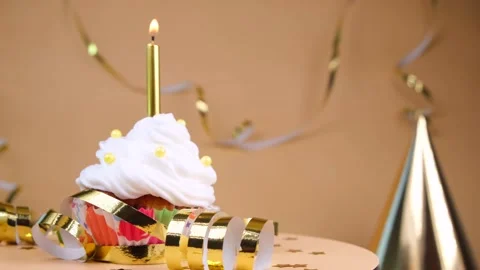 Birthday cake or cupcake with a burning golden candle on a beige background. The Stock Footage 196791492