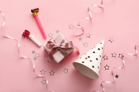 Birthday composition with party  hat, gift box, whistles and confetti on pink Stock Photos