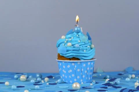 Birthday cupcake with a burning candle, blue background, homemade cakes, ball Stock Photos