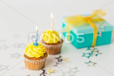 Birthday cupcakes with burning candles and present Stock Photos