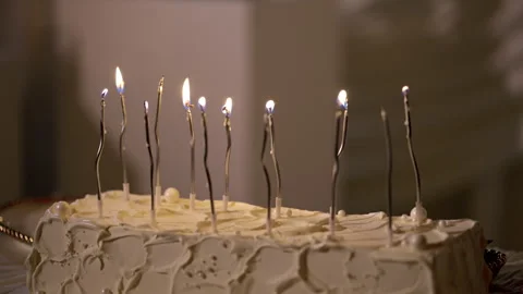Birthday or wedding cake with lit candles glowing in a dimly lit room during a Stock Footage 346790331