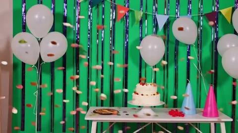 Birthday party setup with cake, balloons, and decorations against green backdrop Stock Footage 317888204