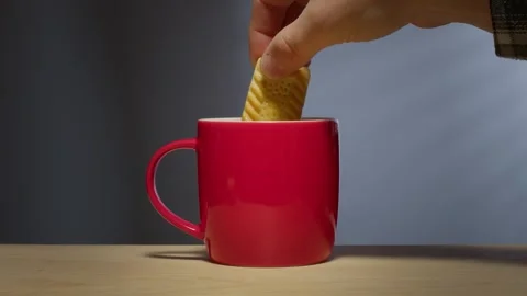 Biscuit dunked into hot drink in a bright red coffee mug Stock Footage 246633736