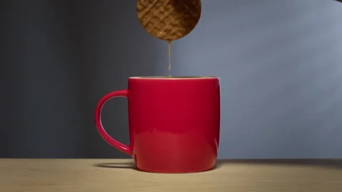 Biscuit dunked into hot drink in a bright red coffee mug Stock Footage 246633749