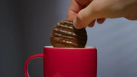 Biscuit dunked into hot drink in a bright red coffee mug Stock Footage 246633755