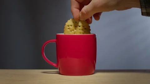 Biscuit dunked into hot drink in a bright red coffee mug Stock Footage 246633758