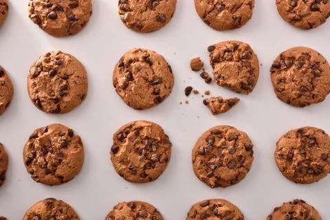 Biscuit pattern with chocolate chips on white table Stock Photos