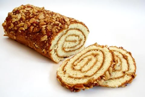Biscuit roll with jam covered with peanuts on a white background. Stock Photos