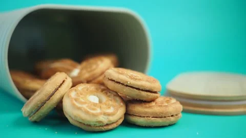 Biscuits with cream filling spilling out of fallen container over bright tu.. Stock Footage 331996789