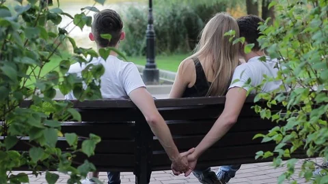 Bisexuality. A guy sitting on a bench secretly holding the h 動画素材 79936727