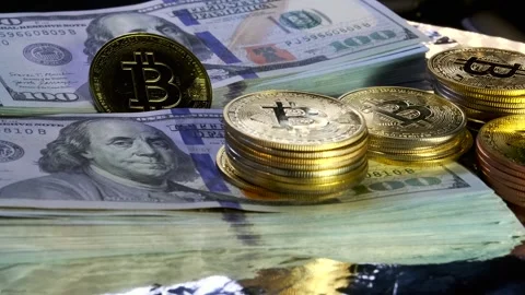 Bit-coin BTC cryptocurrency on 100 US dollars stacks cash slow spinning close up Stock Footage 266901320