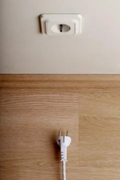 A bit more. White power socket on beige wall at low height from the floor and Stock Photos