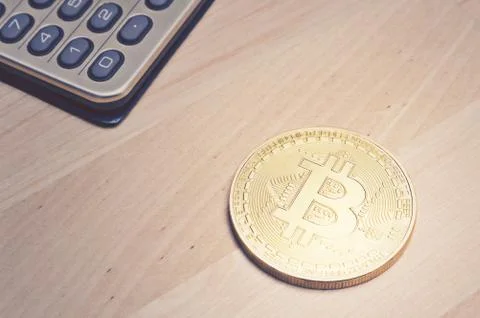 Bitcoin and calculator on table Stock Photos